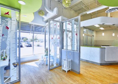 A brightly lit dental clinic reception area and kids' waiting room with colorful decor and birch tree motifs.