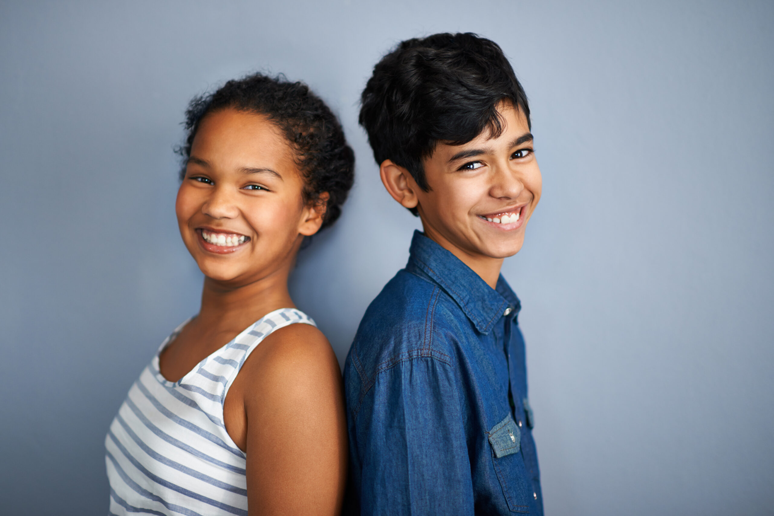 Back to back besties. A cute brother and sister standing isolated on grey